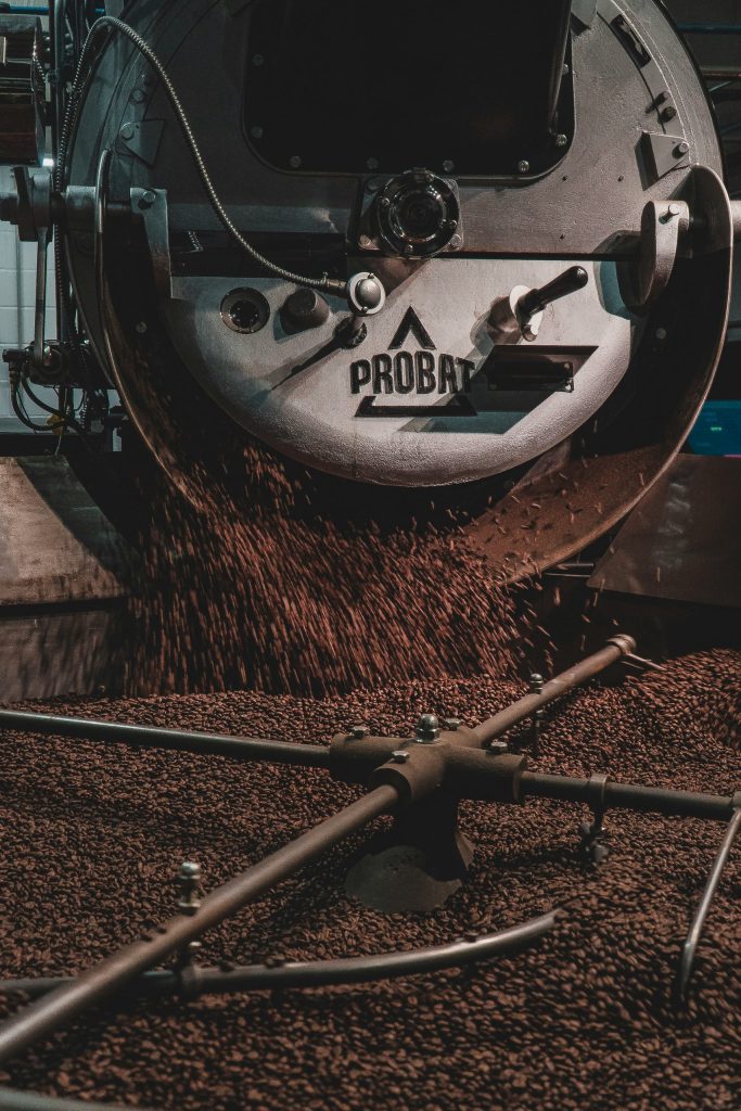 Modernized Probat roaster discharging freshly roasted coffee beans into the cooling sieve.