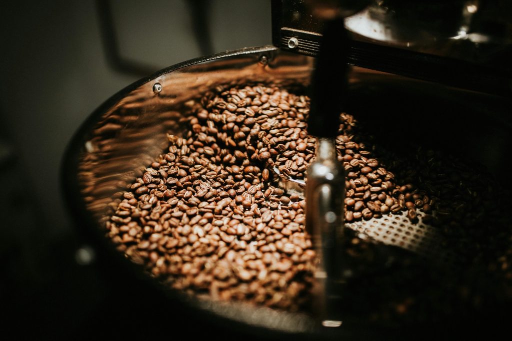 Freshly roasted coffee beans on the cooling tray of a drum roaster during the cooling process in a professional roastery.