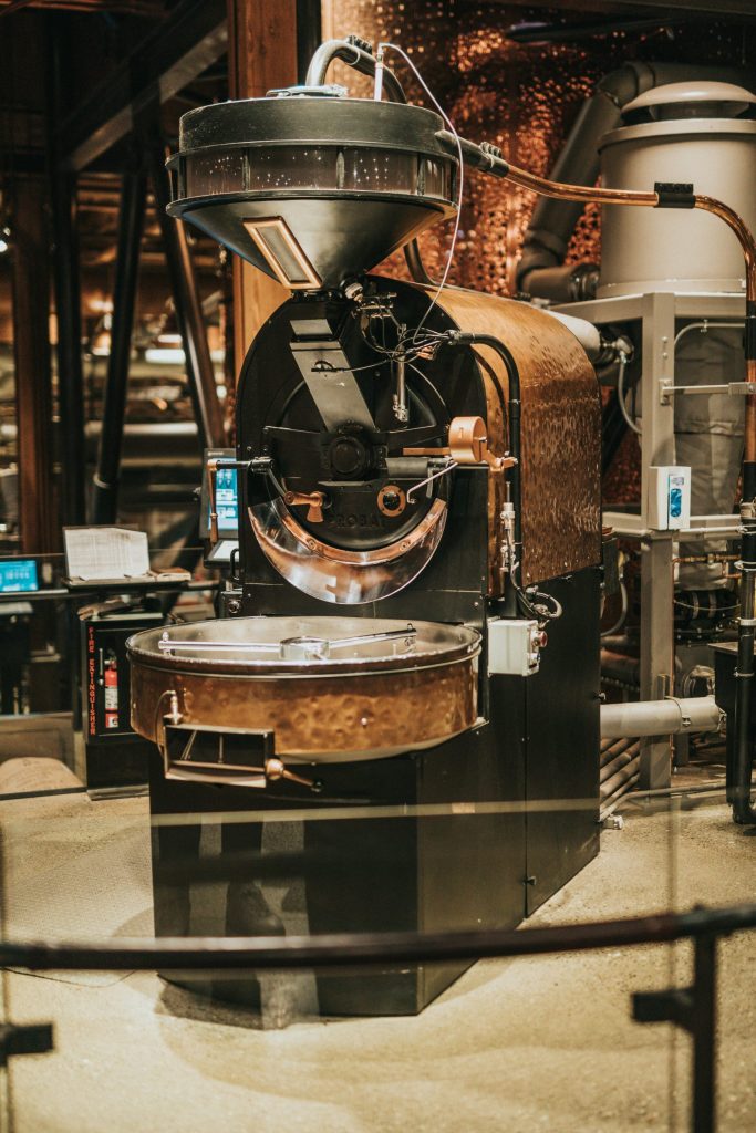 Modern industrial coffee roaster with a classic design and copper elements inside an artisanal roastery.